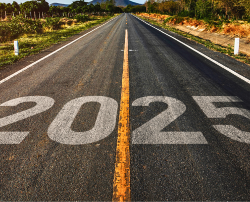 An open road stretching into the horizon with the year '2025' painted on the asphalt, symbolizing a journey toward the future. Surrounded by greenery and mountains in the distance under a warm sunset glow.